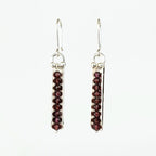 Pair of silver earrings with red gemstones on a white background