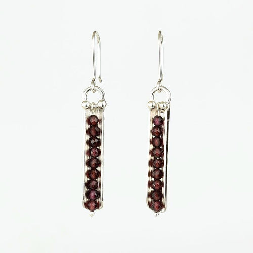 Pair of silver earrings with red gemstones on a white background